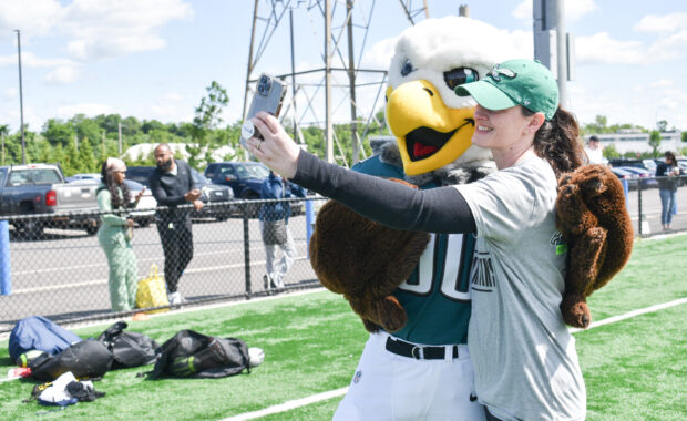 SWOOP the Philadelphia Eagles Mascot taking a photo with a parent at the camp kick off.